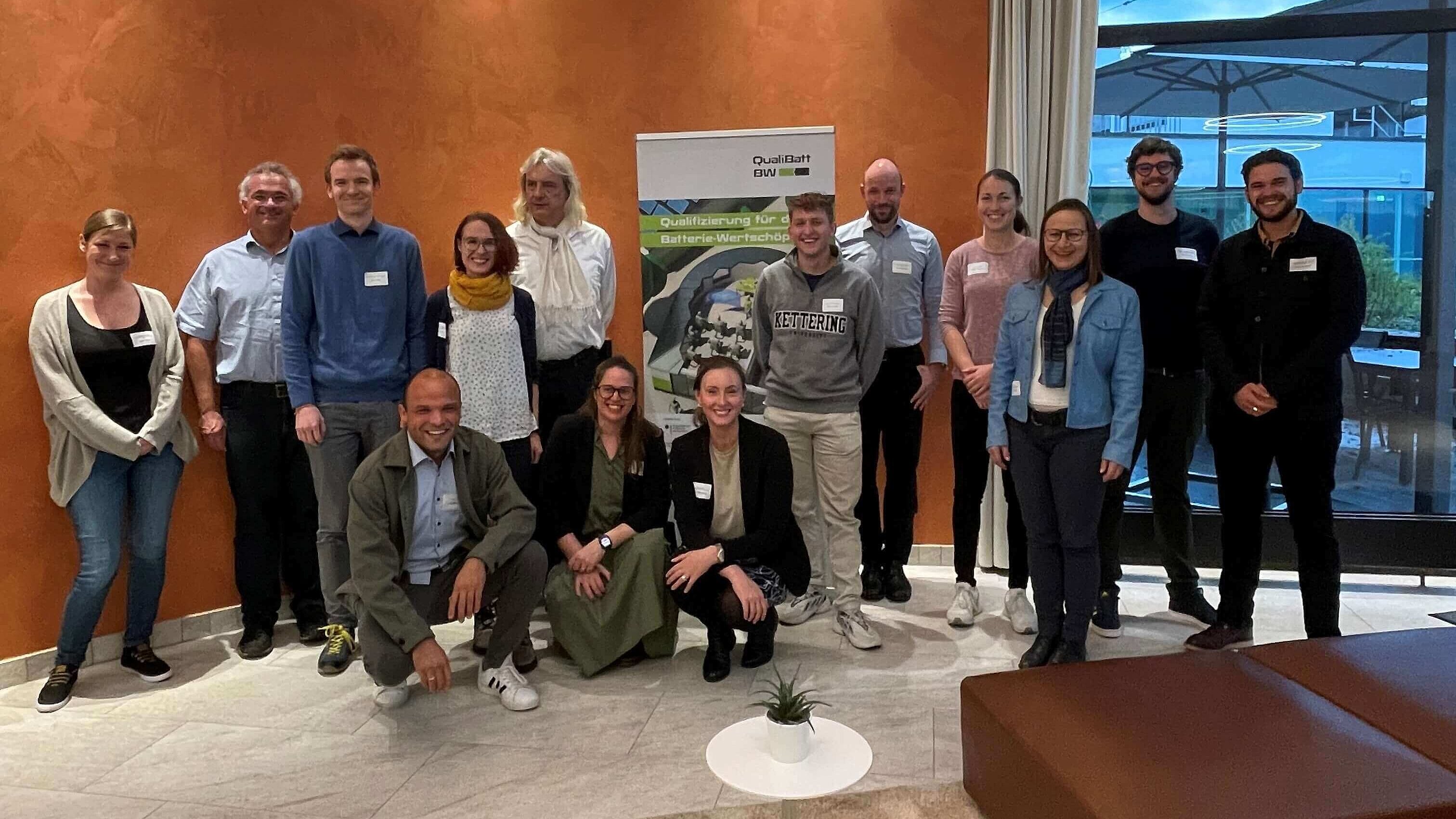 Eine Gruppe von Personen steht vor einem Roll-up des Projektes QualiBattBW.