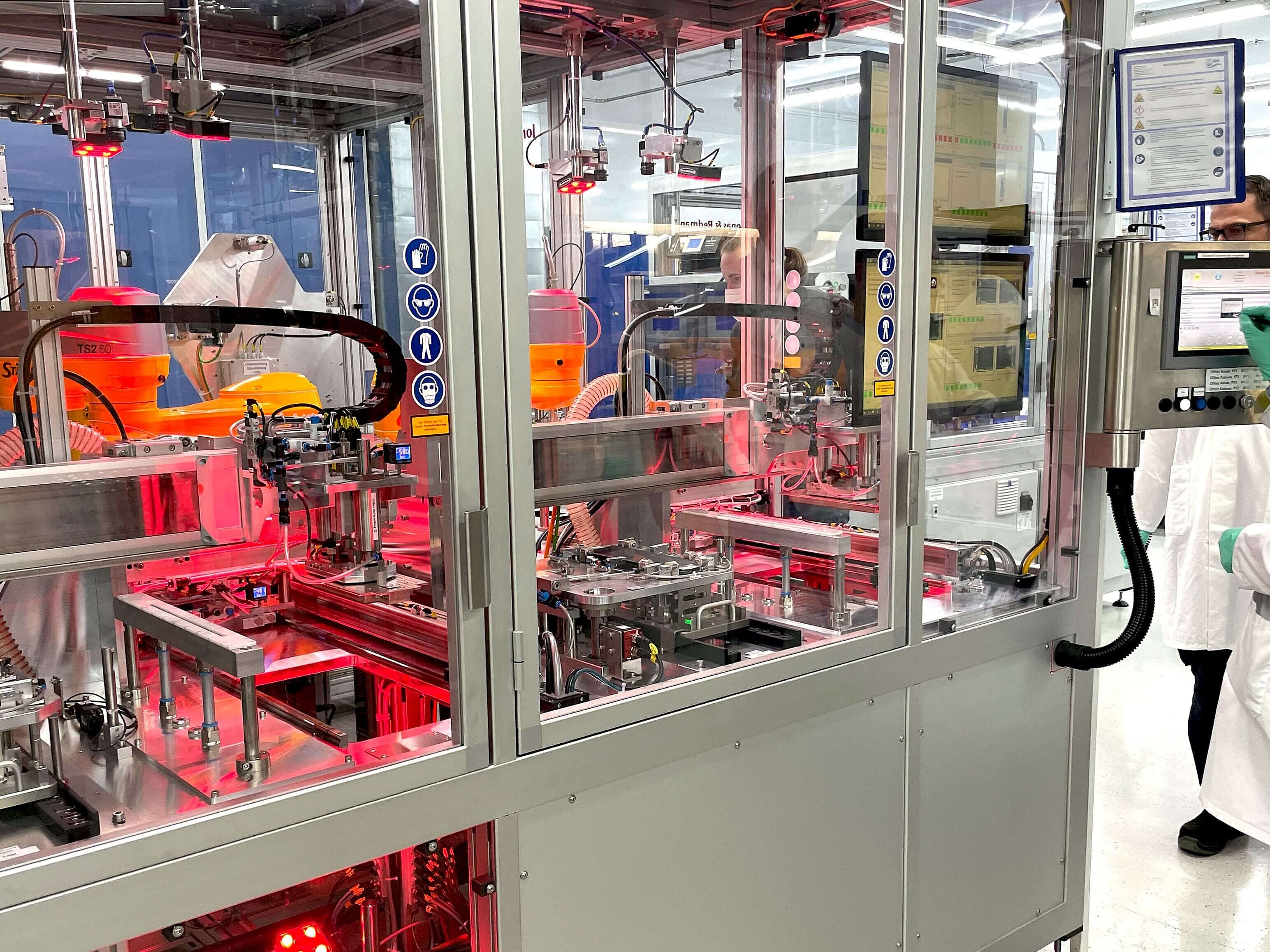 QualiBattBW Modul Sichere Batteriesysteme Forschende in weißem Laborkittel überwachen automatisierte Fertigung von Batteriesystemen in Laborumgebung.